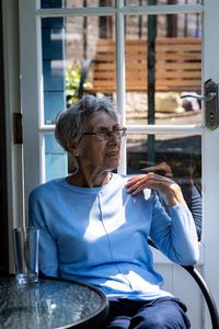 Senior woman sitting at table in restaurant while looking away