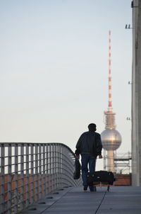 Rear view of man walking on footpath against fernsehturm