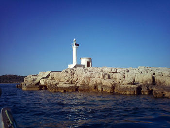 Lighthouse on beach against blue sky