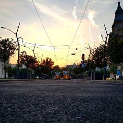 Road passing through city at sunset