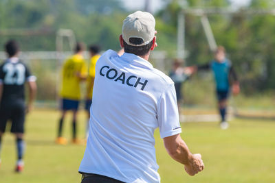 Rear view of man standing on soccer field