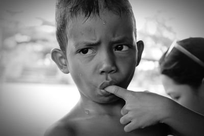 Close-up of shirtless boy with finger in mouth