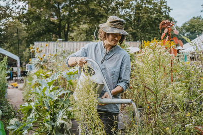 Man in hat watering plants in urban garden