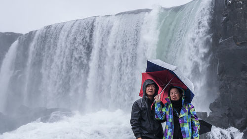 Portrait of couple standing against waterfall