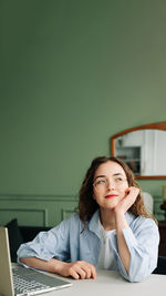 Portrait of young woman using laptop at home