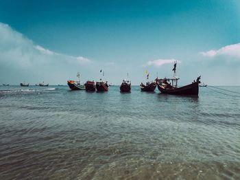 Fishing boats in sea against sky