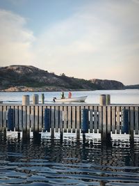 Wooden posts in lake against sky