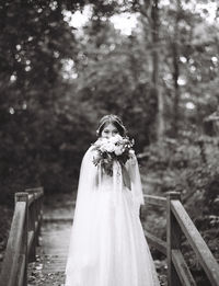 Portrait of bride with bouquet standing on footbridge