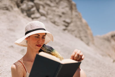 Midsection of woman reading book on beach