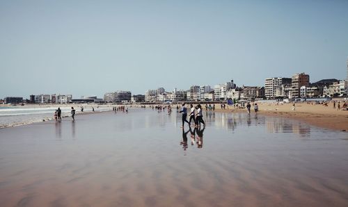 People on beach against clear sky