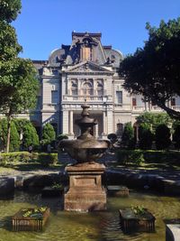 Statue by fountain in park against sky