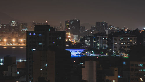 Illuminated buildings in city against sky at night