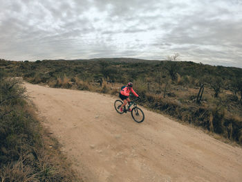 Man riding bicycle on street against sky