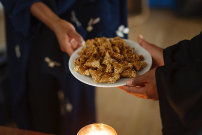 Muslim women wearing abayas gifting and sharing arabic sweets during ramadan