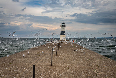 Lighthouse by sea against sky