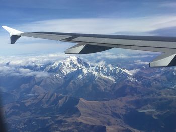 Cropped image of airplane flying over snowcapped mountain