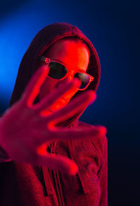 Close-up portrait of woman wearing sunglasses against blue background