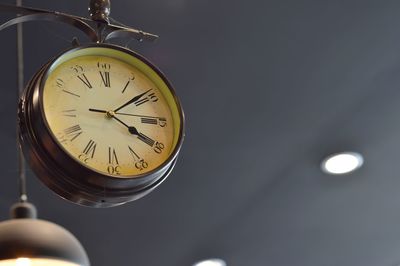 Low angle view of clock against ceiling