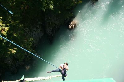 High angle view of woman skydiving over river in forest