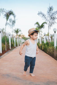 Full length of boy walking by plants against trees