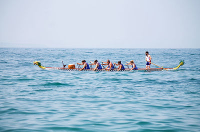 People on boat in sea against clear sky