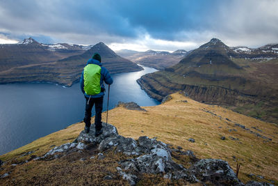 Rear view of man standing on mountain against sky