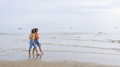 Full length of children on beach against sky