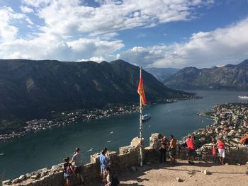 People on mountain by river against sky