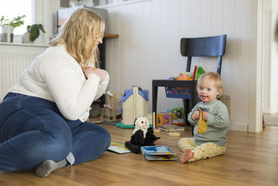 Side view of boy playing with toy on floor at home