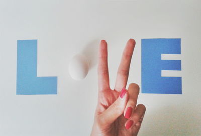 Egg and female hand completing love text on wall