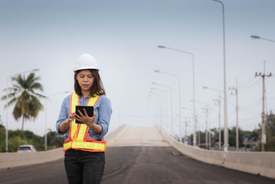 Young man using mobile phone while standing on road