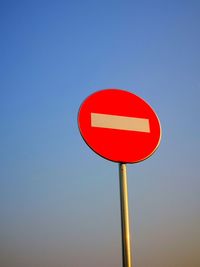 Low angle view of road sign against clear blue sky