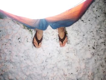 Low section of person standing on sand at beach