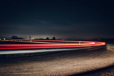 Light trails on road against sky at night