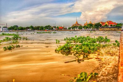 View of buildings at waterfront against cloudy sky