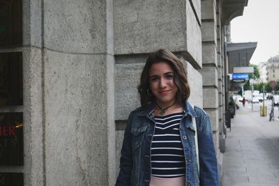 Portrait of beautiful woman standing against building in city