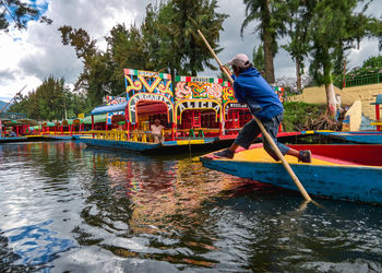 Man standing by boat on river against trees