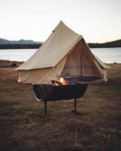 Tent on bonfire against lake