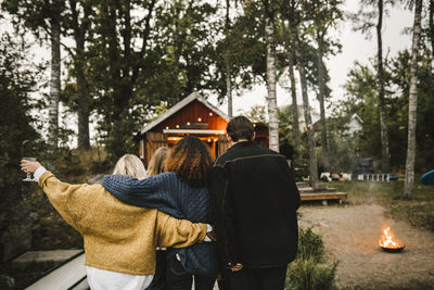 Rear view of people walking against trees