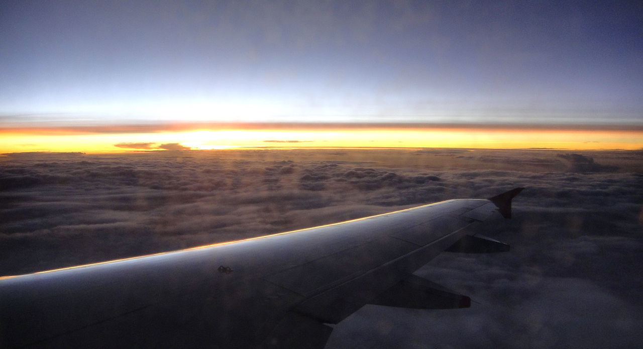 AIRPLANE FLYING OVER CLOUDS DURING SUNSET