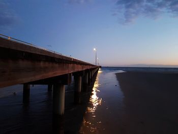 Pier on sea against sky at sunset