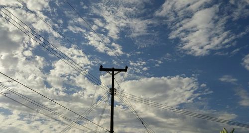 Low angle view of electricity pylon against cloudy sky