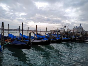 Boats moored in canal against cloudy sky