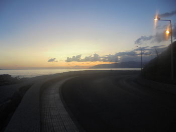 Empty road against sky during sunset