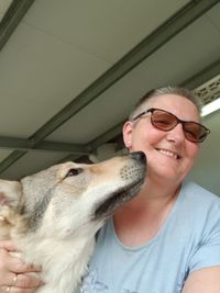 Portrait of smiling mature woman holding dog at home