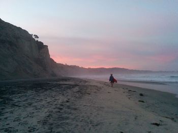 Woman on beach against sky during sunset