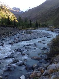 Scenic view of river by mountains against sky