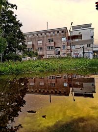 Reflection of building in lake against sky in city