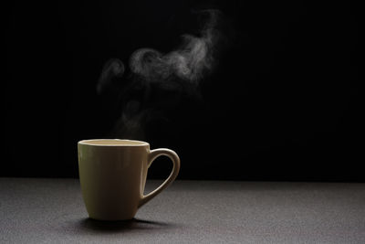 Close-up of coffee cup on table against black background