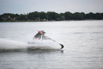 Man riding jet boat on lake against sky
